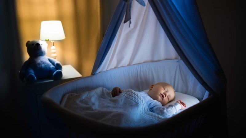 Bildet viser en baby som ligger i en babyseng og sover
