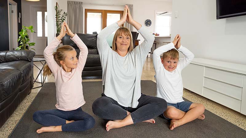 Mot og to barn som prøver yoga.