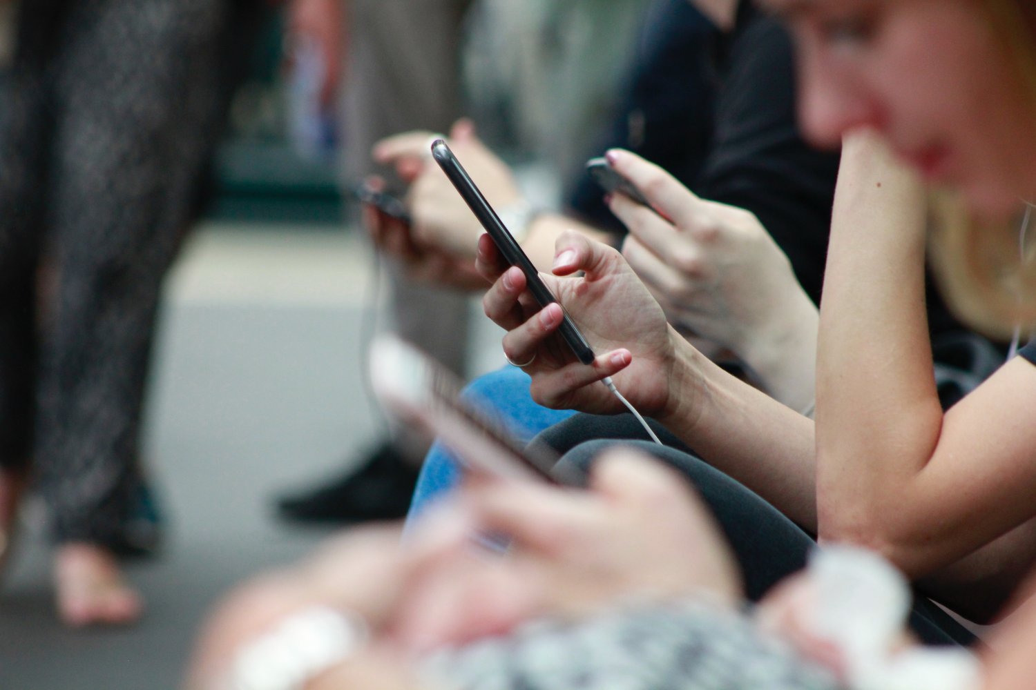 en gruppe mennesker stirrer på mobiltelefonene sine