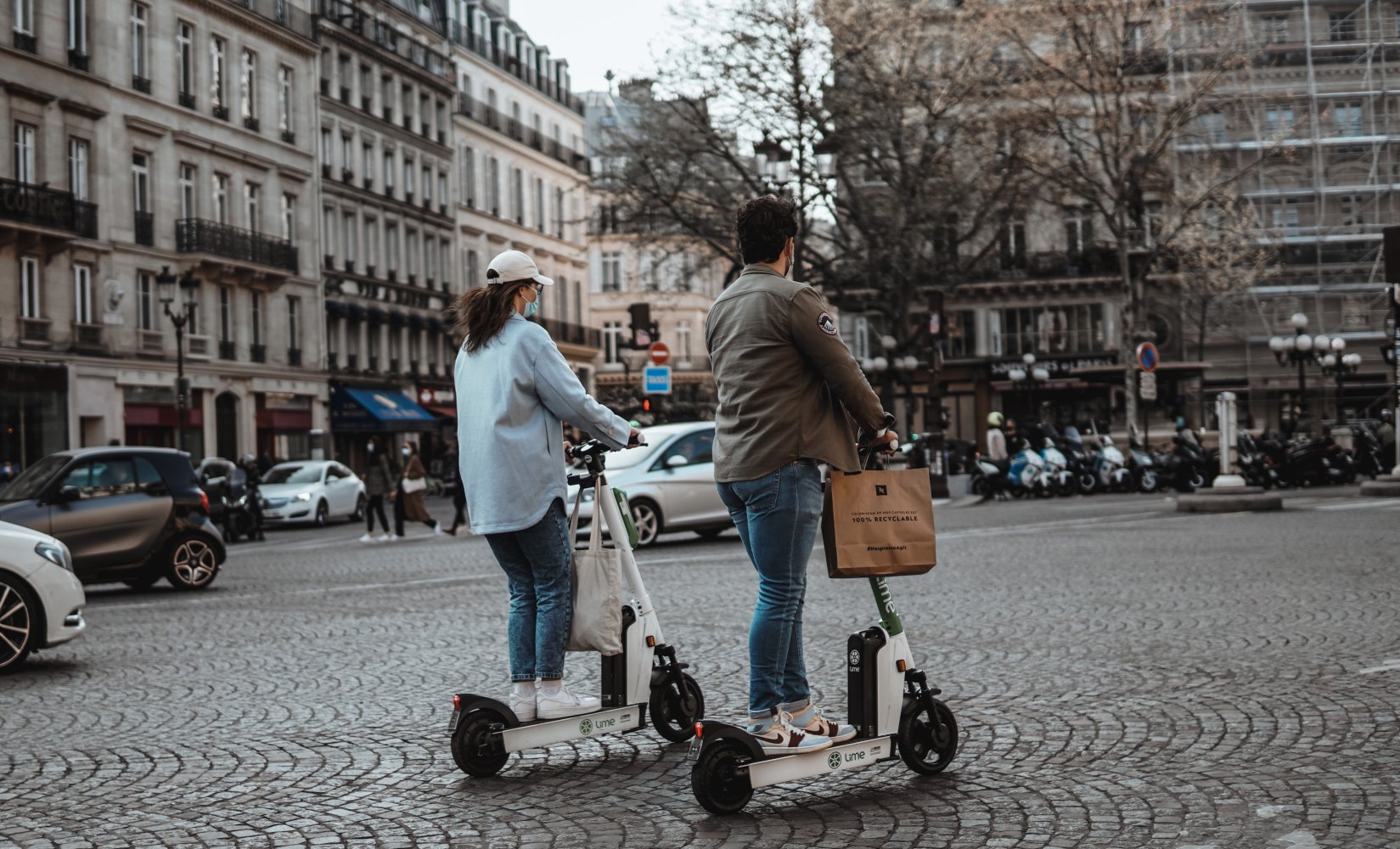 En jente og gutt på hver sin elsparkesykkel i Paris.