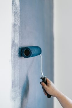 Blå maling med rulle på vegg.