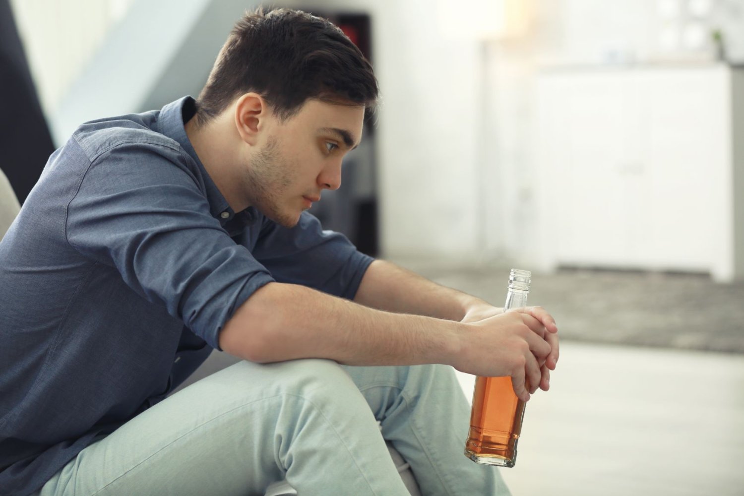 Bildet viser en ung mann/gutt som sitter hjemme og drikker