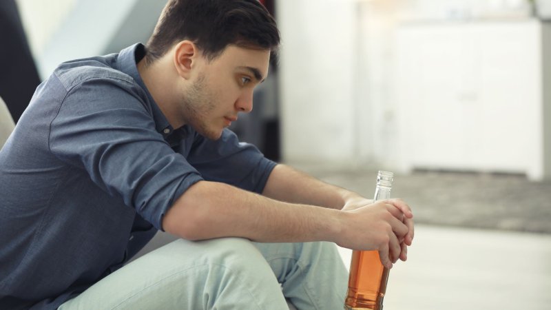 Bildet viser en ung mann/gutt som sitter hjemme og drikker