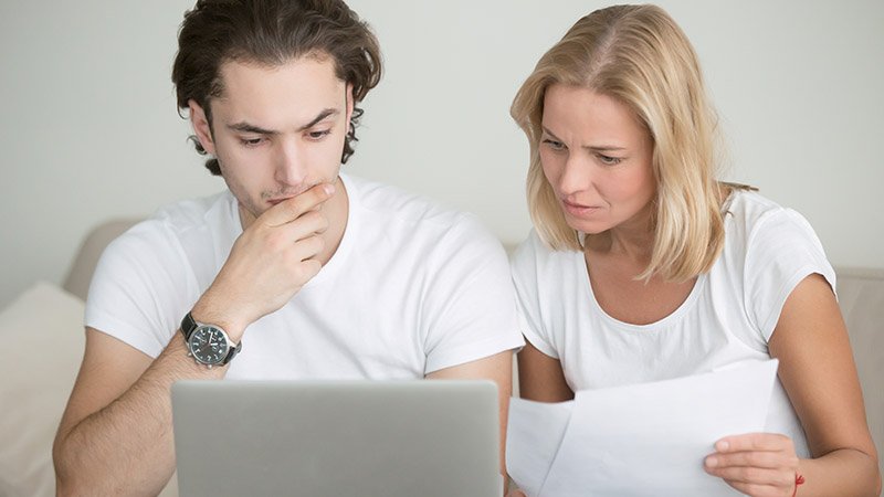 Mor og sønn med papirer foran datamaskin.