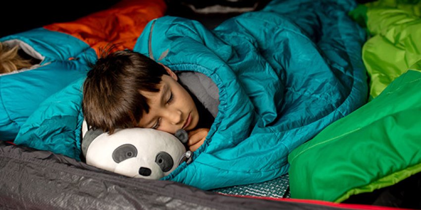 Gutt som sover i sovepose på leirskole.