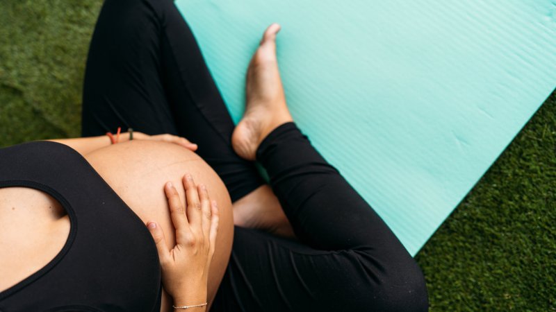 Gravid kvinne på treningsmatte. Gress