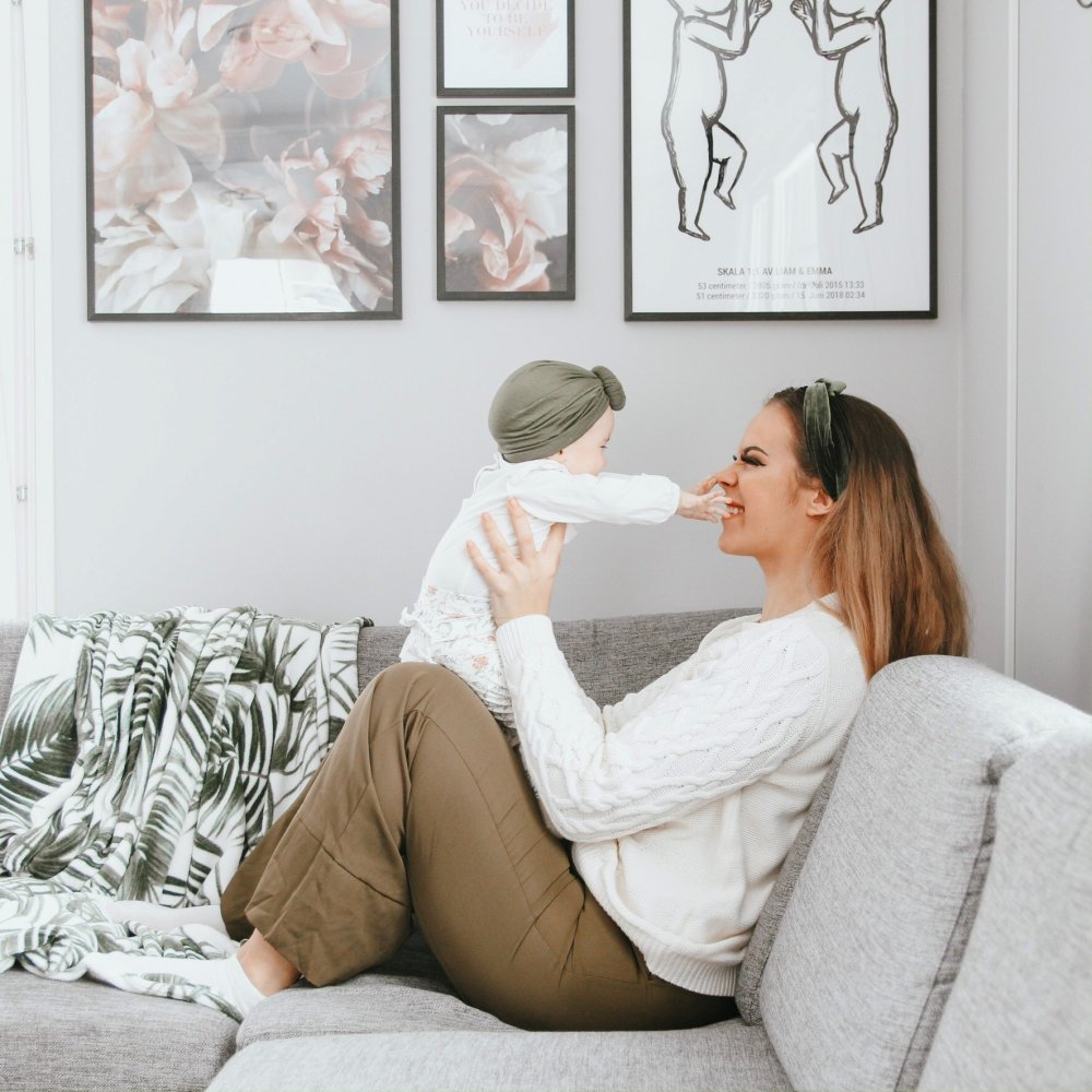 Bildet viser influenser Sara Emilie Tandberg, som sitter i sofaen sammen med babyen sin.