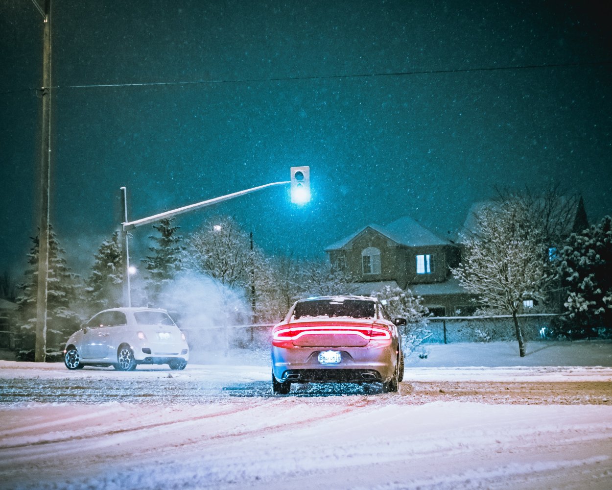To biler i et veikryss på vinterføre