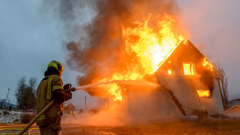 Bildet viser en brannmann som slukker en landbruksbrann