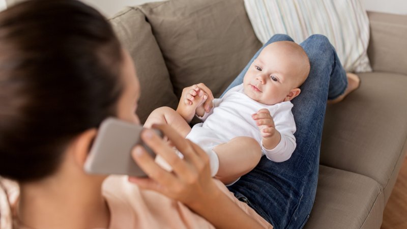 Baby. Mamma. Sitter på fanget. Telefon