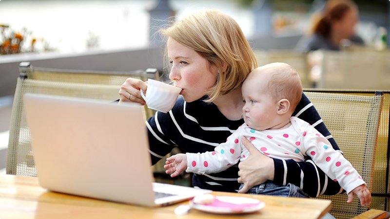Mor og baby. Bærbar PC. Kaffekopp. Utested.