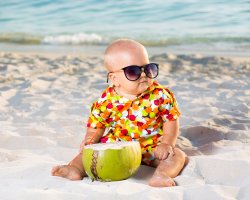 Baby på badestrand. solbriller. kokosnøtt. sugerør.