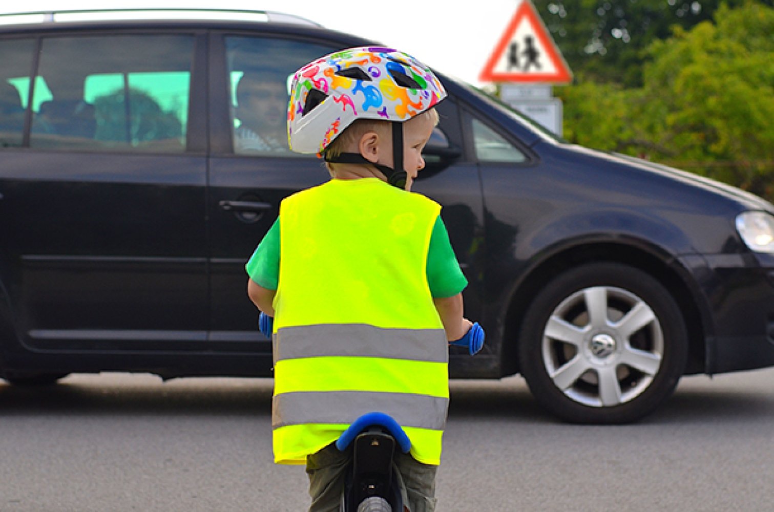 Bildet viser en liten gutt som sykler med hjelm og refleksvest