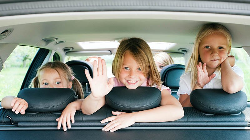 Tre barn i baksetet på en bil.