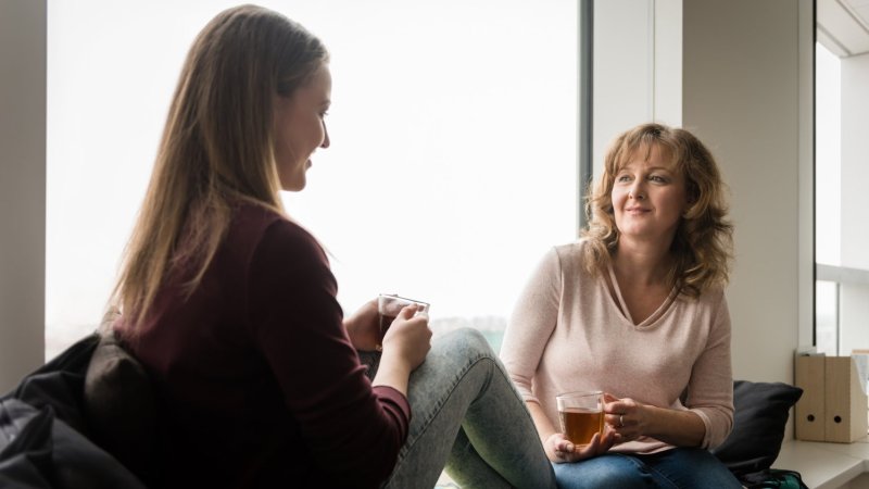 Bildet viser en mor og en datter som sitter og snakker sammen, med en kopp te. 