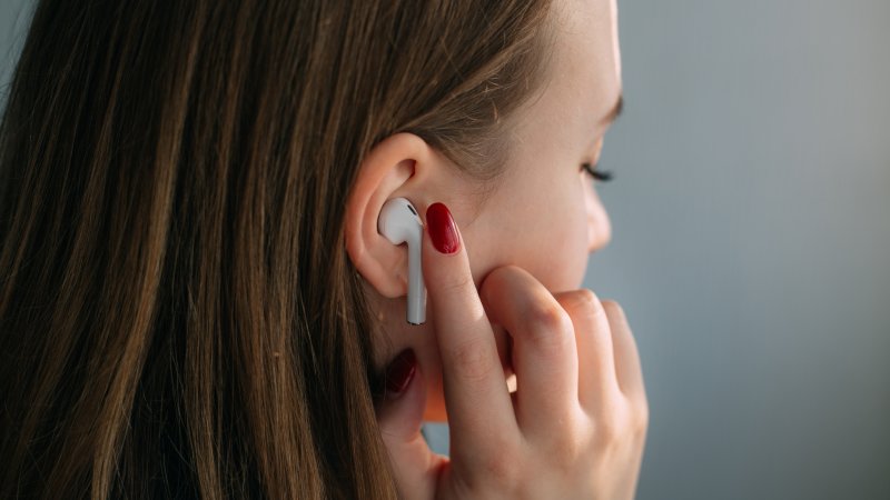 En ung person lytter til trådløse hodetelefoner
