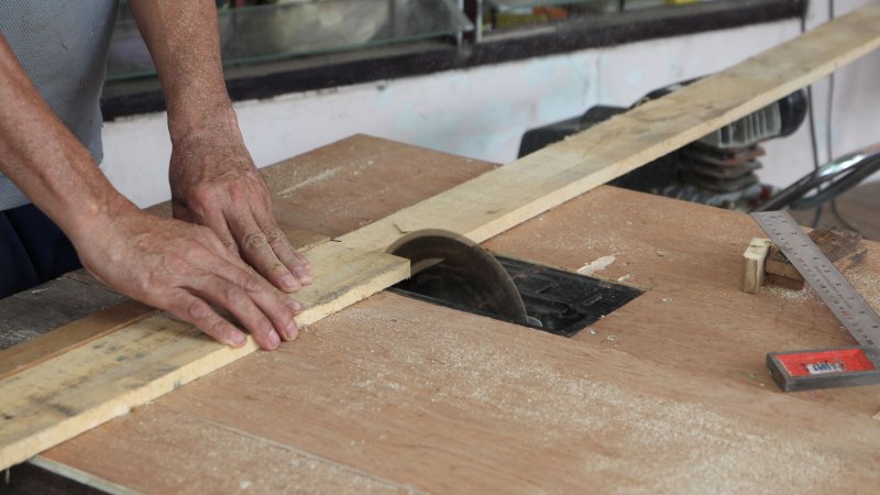 Bildet viser en snekker som kapper en planke.