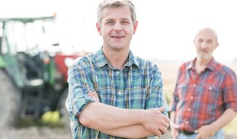 Far og sønn foran en traktor.