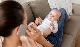 Baby. Mamma. Sitter på fanget. Telefon