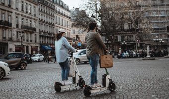 En jente og gutt på hver sin elsparkesykkel i Paris.