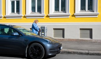 Kvinne kobler elbil til et ladepunkt i gata