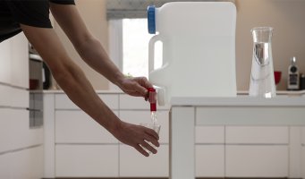 Mann heller vann fra en vanndunk.