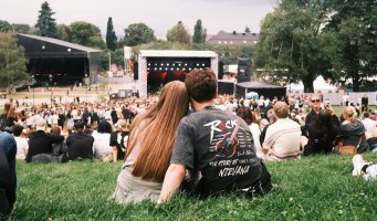 Ungt par ser ned på scenen på en musikkfestival i Oslo, sett bakfra