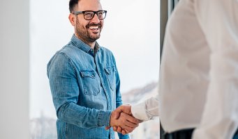 To menn tar hverandre i hånda, smilende mann.