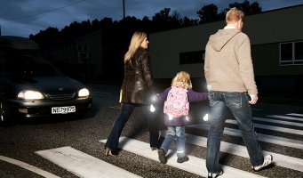 Familie med refleks går over fotgjengerfelt på kvelden