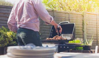 Mann som griller middag i hagen
