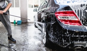 Bildet viser en mann som vasker bilen med høytrykkspyler
