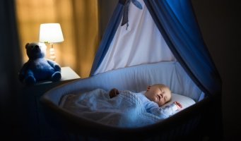 Bildet viser en baby som ligger i en babyseng og sover