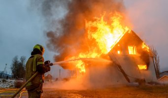 Bildet viser en brannmann som slukker en landbruksbrann