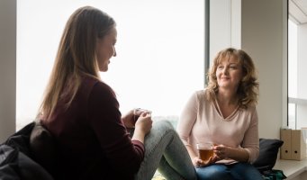 Bildet viser en mor og en datter som sitter og snakker sammen, med en kopp te.