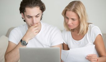 Mor og sønn med papirer foran datamaskin.