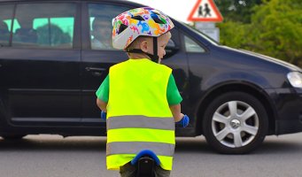 Bildet viser en liten gutt som sykler med hjelm og refleksvest