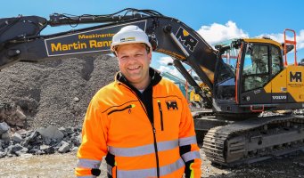 Svein-Erik Ryen står foran en gravemaskin og smiler.