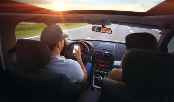 Biltur. Sjåfør bruker mobilen bak rattet.