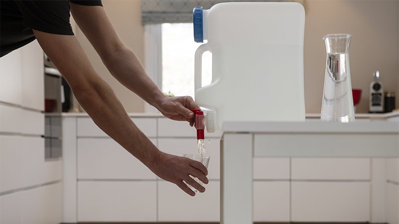 Mann heller vann fra en vanndunk.